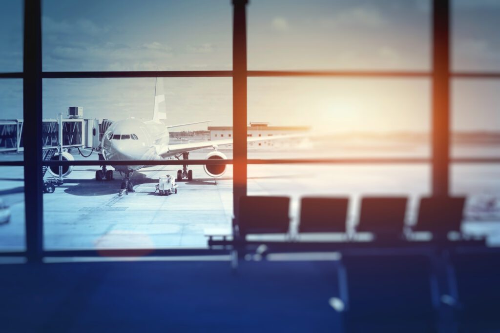 A Photo of an Airplane at a Gate With a Sunrise in the Background