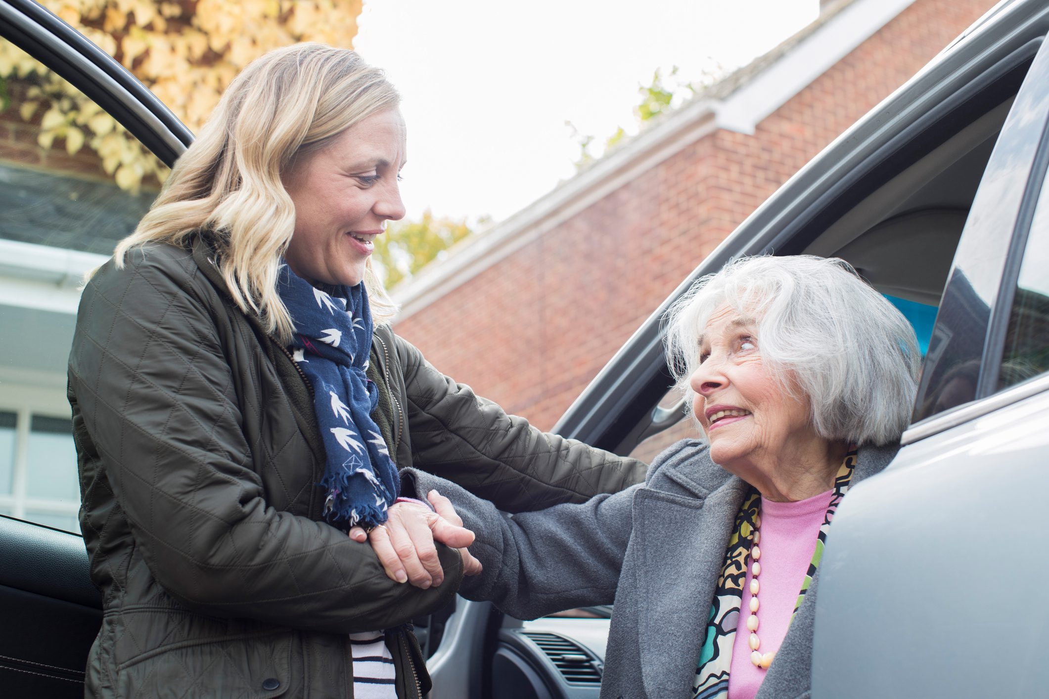 Attractive Woman Helping Senior Woman a Lift in a Car
